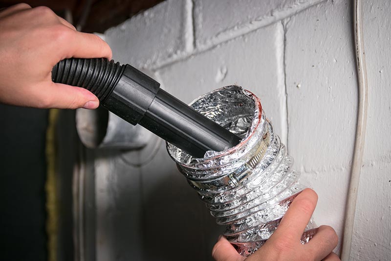 a dryer vent being cleaned with a vacuum
